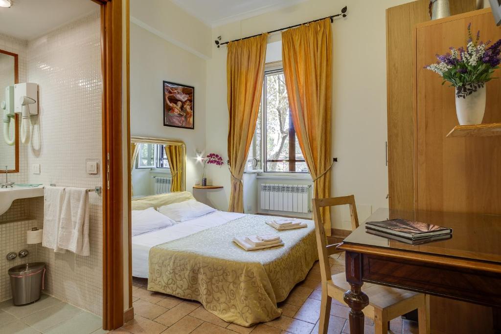 Schlafzimmer mit einem Bett, einem Tisch und einem Spiegel in der Unterkunft At Rome St. Peter's in Rom