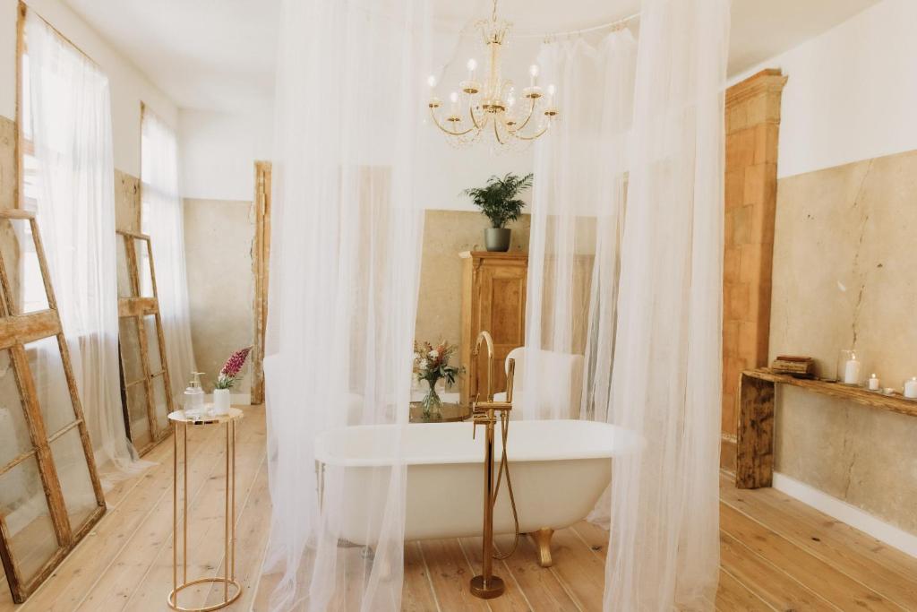a white bathroom with a tub and a chandelier at Artisan in Kuldīga