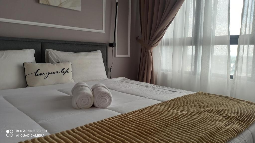 a bed with two towels on it with a window at Zulanie Suite Troika Residence, SPACIOUS AND COZY WITH POOL, Free Wifi & Netflix in Golden Triangle of Kota Bharu in Kota Bharu