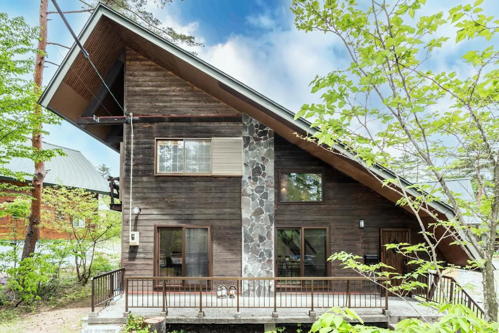 Cette maison en bois est entourée d'une terrasse couverte. dans l'établissement Ringo Cottage, à Hakuba