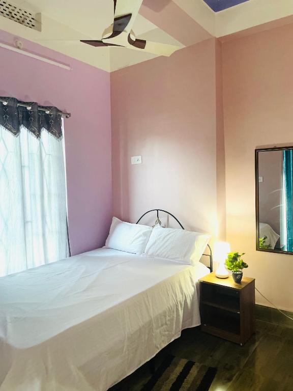 a bedroom with a white bed and a pink wall at Renade Leisure Stay in Agartala