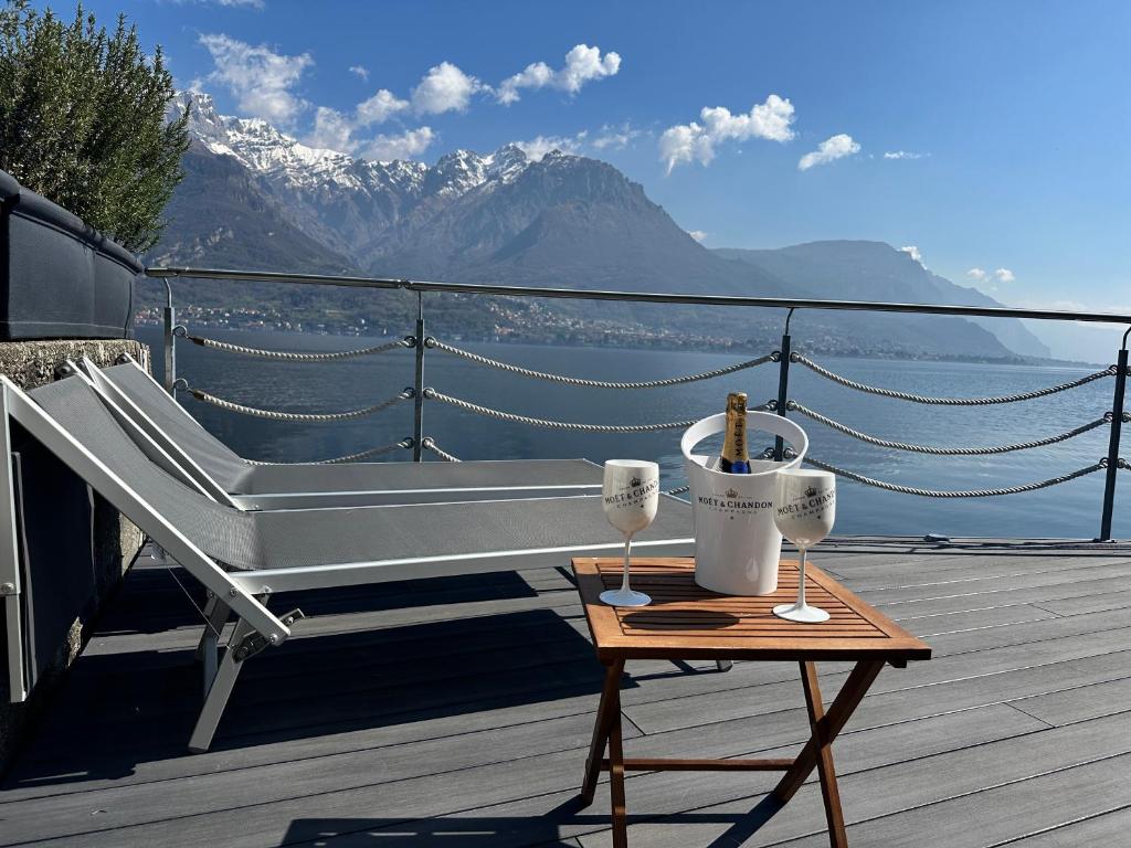 a bench on a deck with a table with wine glasses at Al Molo 5 - Lake Front in Oliveto Lario