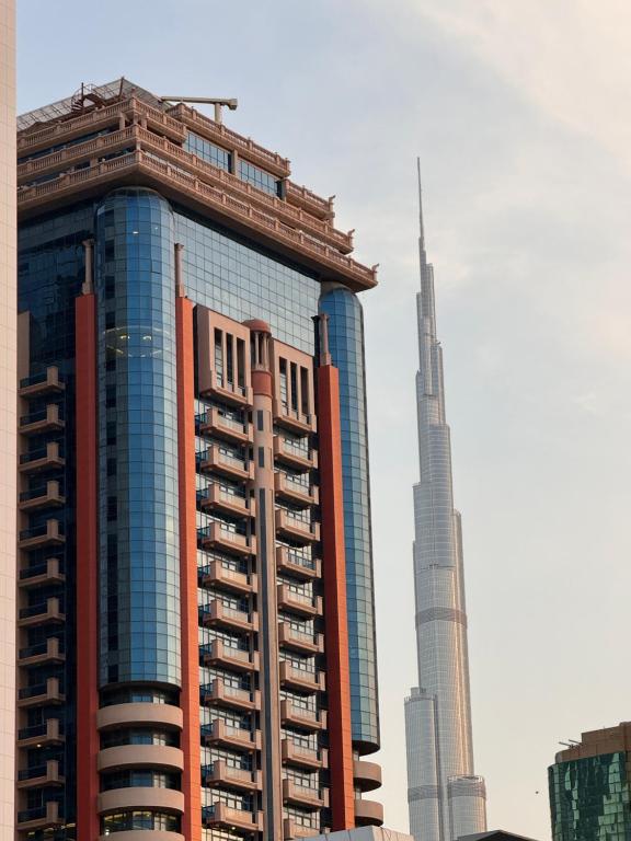 um edifício alto com o burj khalifa no fundo em Emirates Grand Hotel em Dubai