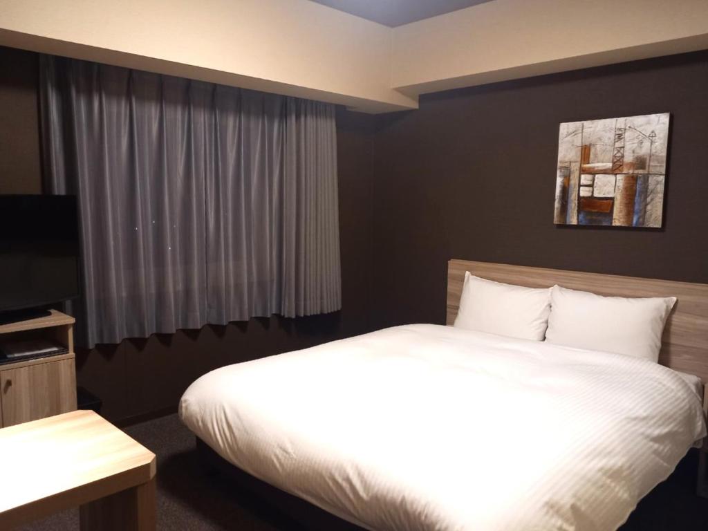 Postel nebo postele na pokoji v ubytování Hotel Route-Inn Yamanashi Chuo