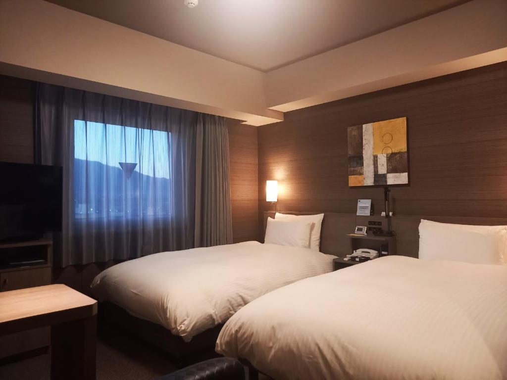Postel nebo postele na pokoji v ubytování Hotel Route-Inn Yamanashi Chuo