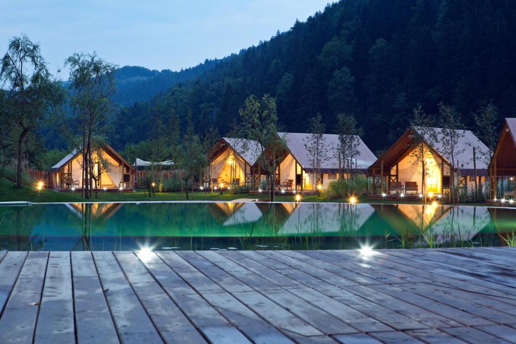 a resort with a swimming pool at night at Charming Slovenia - Herbal Glamping Resort Ljubno in Ljubno