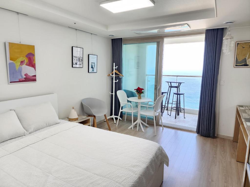 a bedroom with a bed and a table with chairs at Sokcho Summitbay 1807 "Panoramic Ocean View" in Sokcho