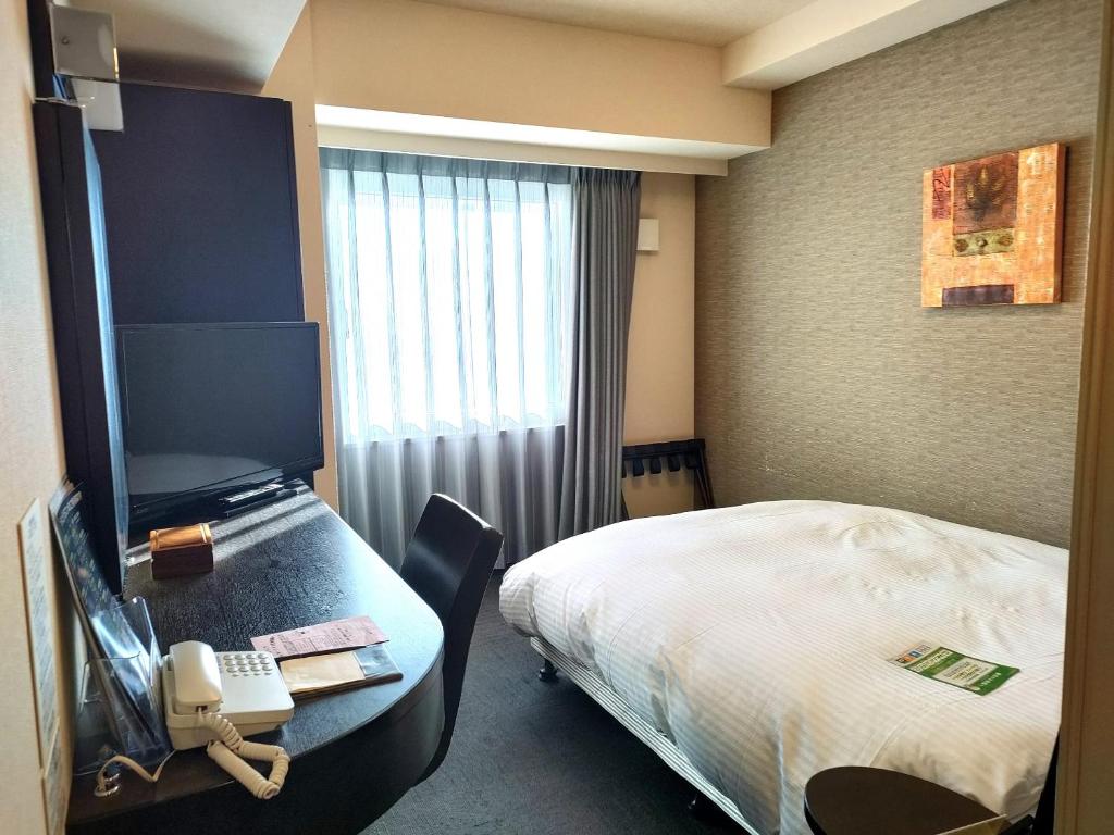 宮崎的住宿－Hotel Route-Inn Miyazaki Tachibana Dori，酒店客房,配有一张床和一张书桌上的电话