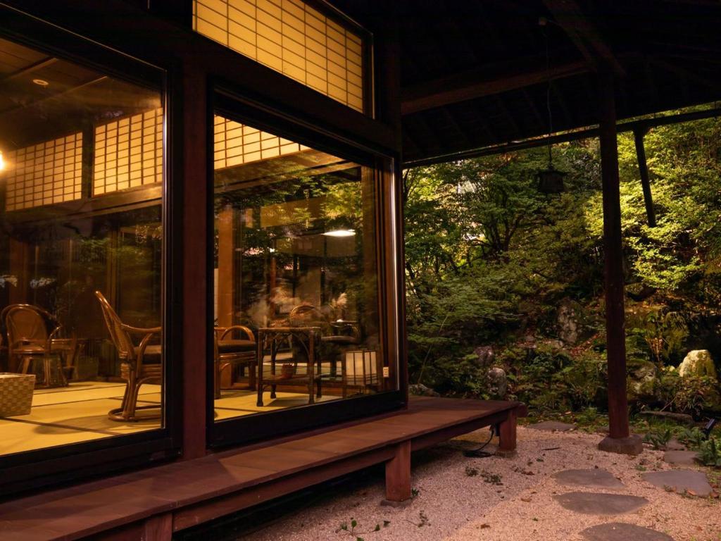 eine abgeschirmte Veranda eines Hauses mit einem Tisch und Stühlen in der Unterkunft Chousenkaku Kameya in Shimo-suwa