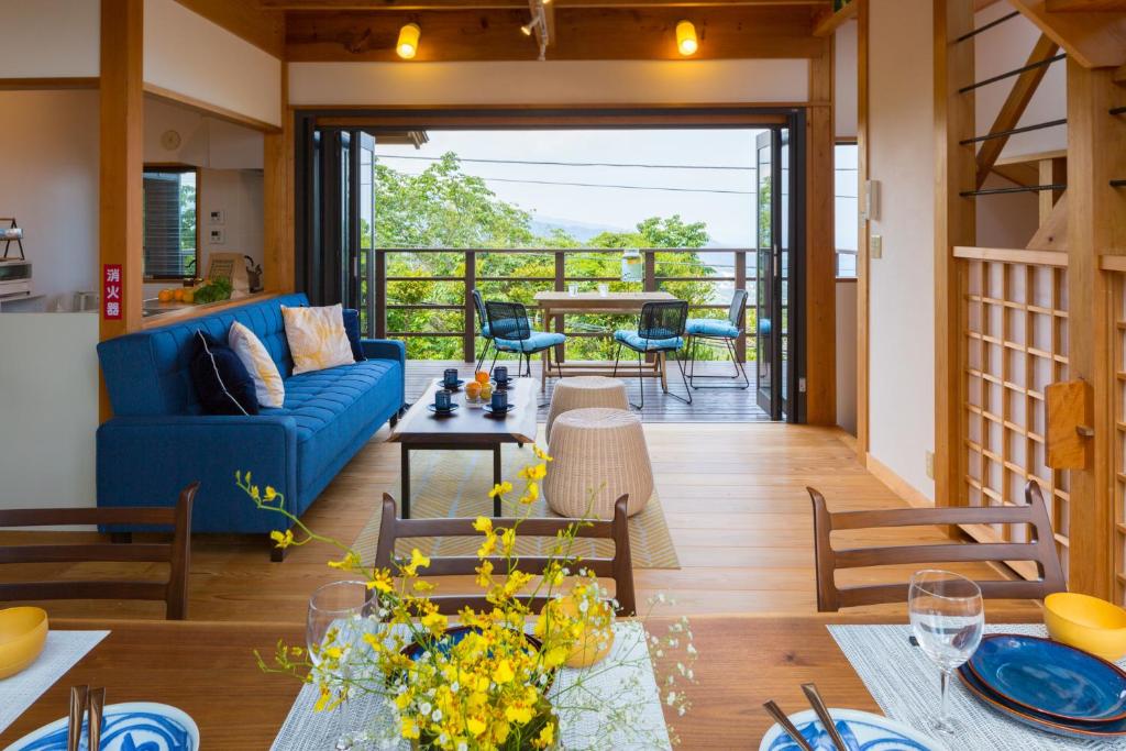 スイートヴィラ オーシャンビュー熱海⾃然郷 في أتامي: غرفة معيشة مع أريكة زرقاء وطاولة