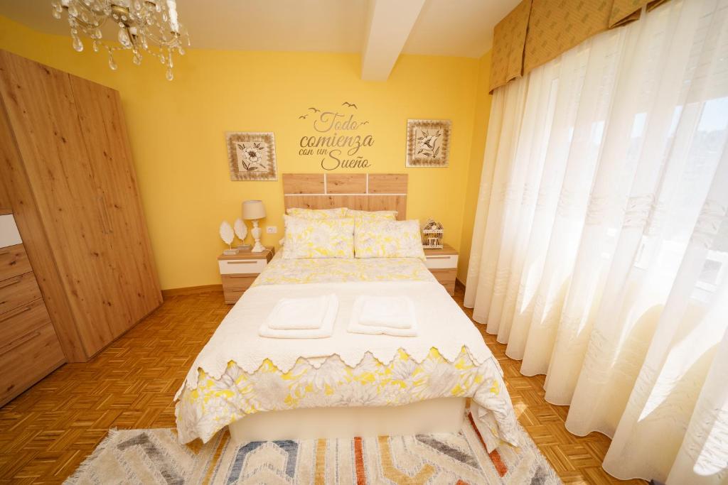 - une chambre avec un grand lit aux murs jaunes dans l'établissement Antoxos Sacra Home II, à Chantada