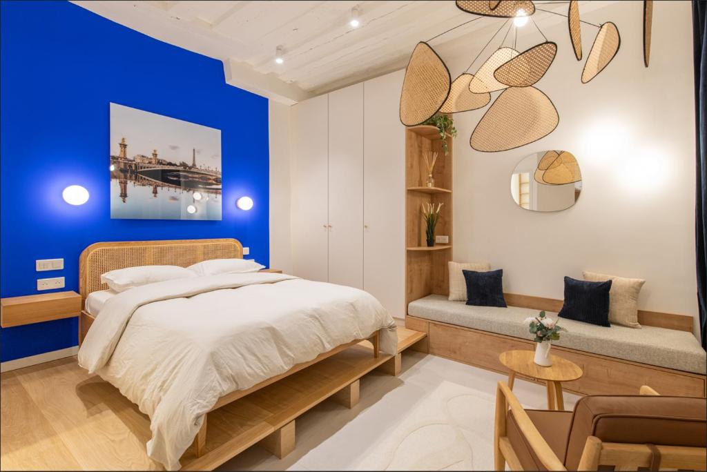 - une chambre avec des murs bleus, un lit et un banc dans l'établissement Geranimus : Heart of Paris Montorgeuil, à Paris