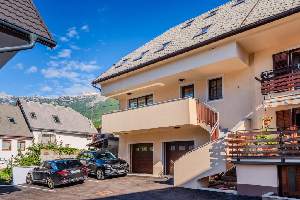 a house with two cars parked in a parking lot at Penzion Hosnar, hiša Mišc in Bovec