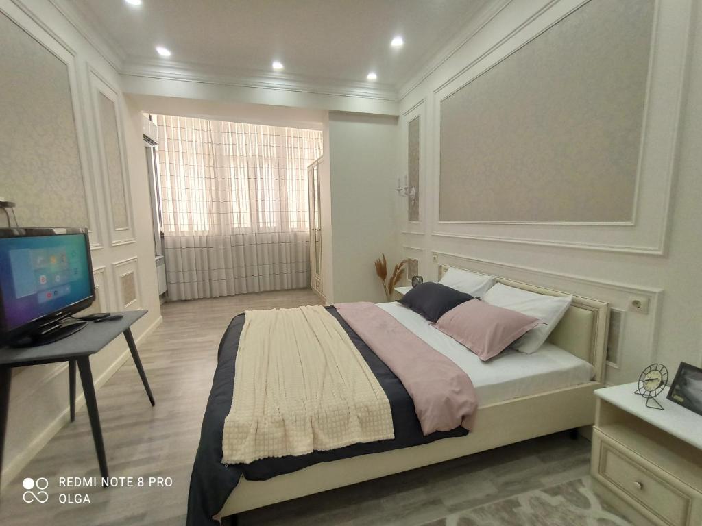 une chambre avec un lit, un bureau et une télévision dans l'établissement Двухкомнатные апартаменты в 16 мкр ЖК Panorama 11 дом, рядом с ТРК Актау, стадион Мунайши, à Aktau