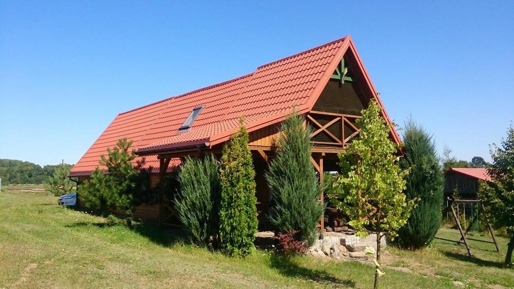 a large wooden house with a red roof at Dom letniskowy ORCHIDEA in Chrzanowo