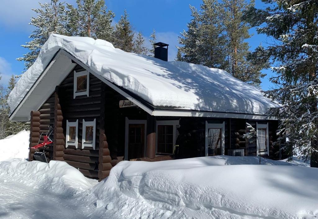 a log cabin with snow on the roof at Ruska 2, Ylläs - Log Cabin with Lake and Fell Scenery in Äkäslompolo