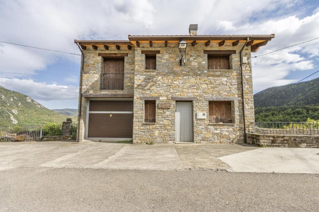 een stenen huis met een garage voor een berg bij Casa Irene in Calvera