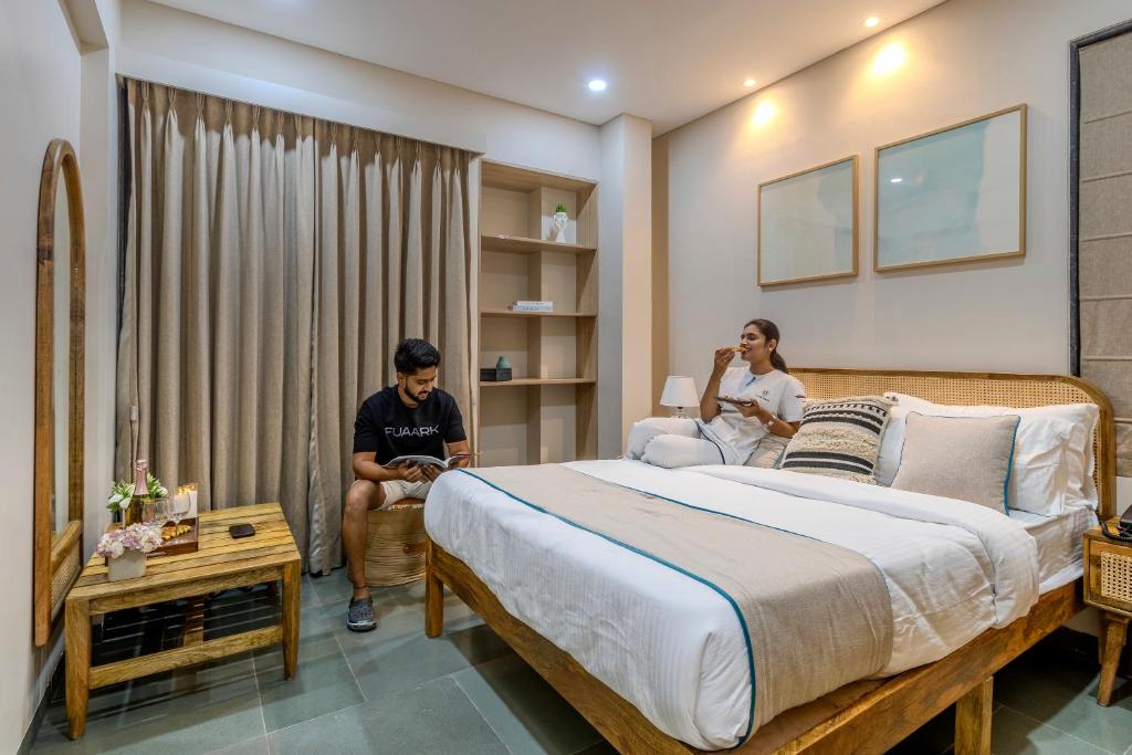 two people sitting in a bedroom with a large bed at Hotel Tattva Suites in Pune