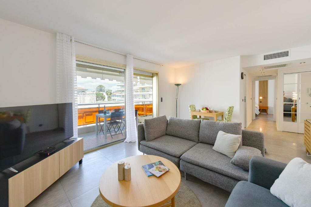 un salon avec un canapé, une télévision et une table dans l'établissement Renovated 1Br apartment terrace walk to beach, à Cannes
