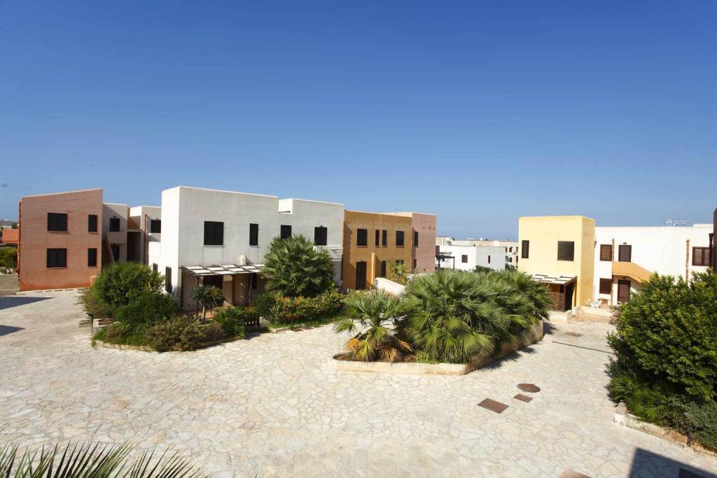a courtyard of a building with palm trees and buildings at Residence Favignana in Favignana