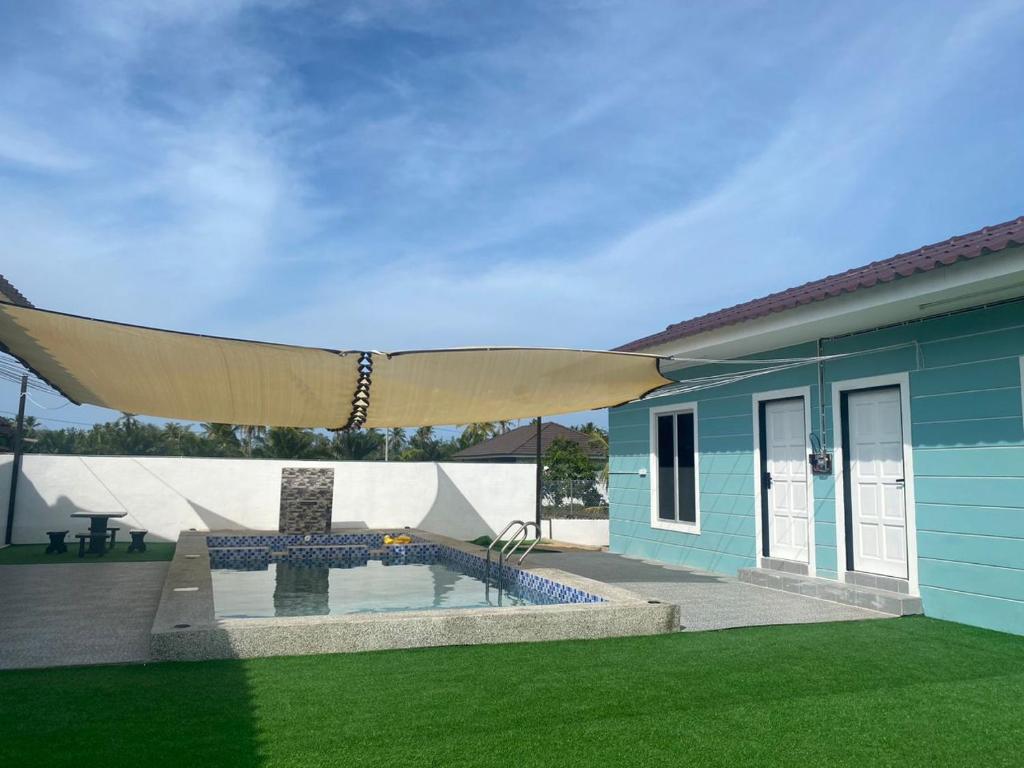 a blue house with a swimming pool and a large umbrella at Triple S Homestay Bachok in Bachok