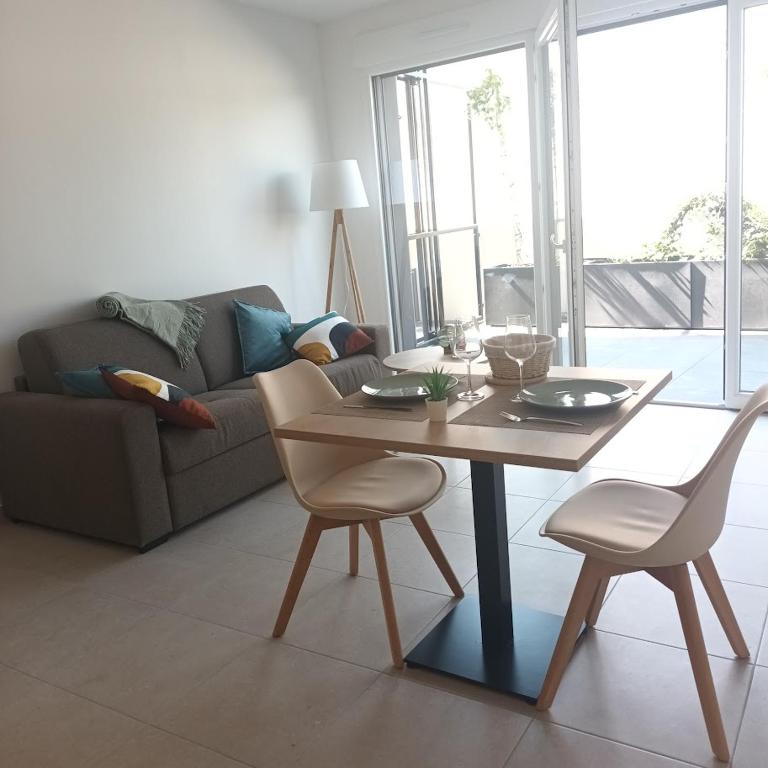 a living room with a table and chairs and a couch at Cosy Diem Cap d'Agde in Cap d'Agde