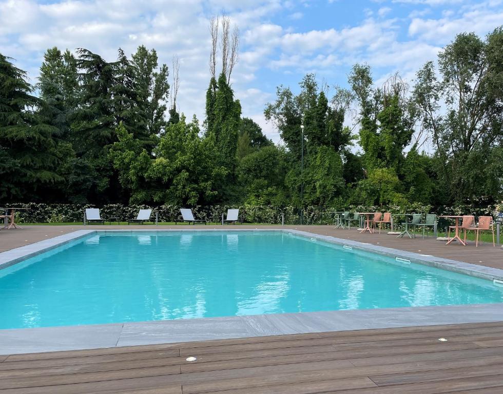 une grande piscine bleue avec des tables et des chaises dans l'établissement Belstay Venezia Mestre, à Marghera