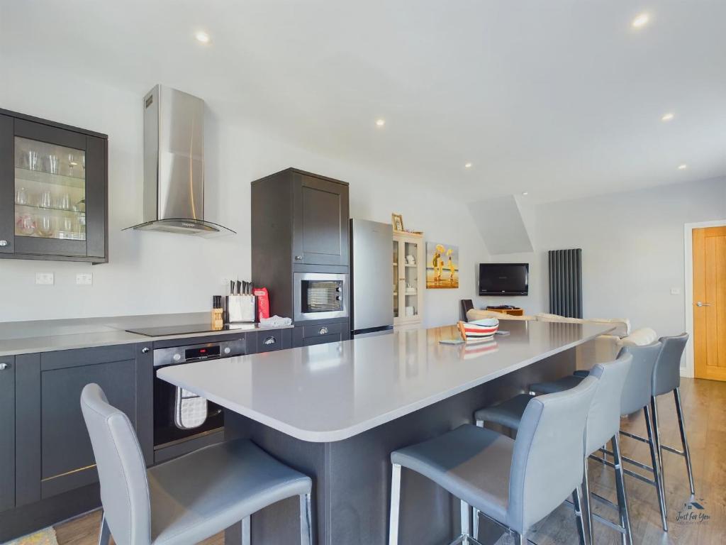 a kitchen with a large white counter and chairs at Seaside Cottage, Moments from Ryde's Golden Sands, Sleeps 4 in Ryde