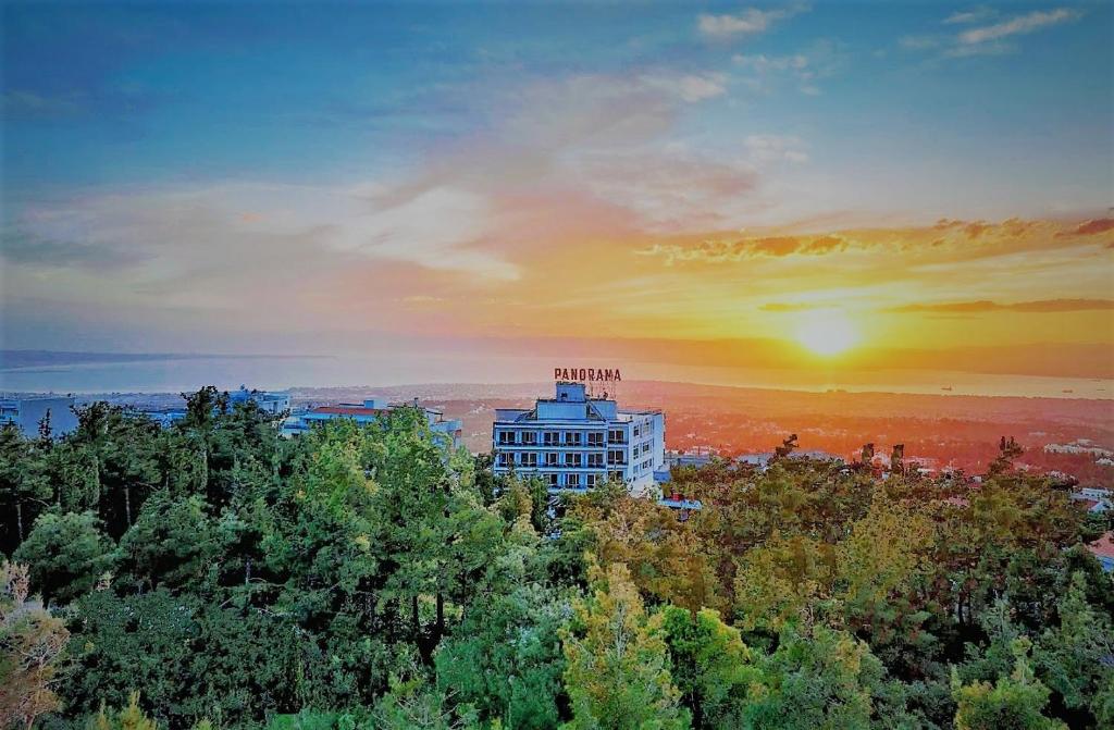 um edifício no meio de árvores com um pôr-do-sol em Hotel Panorama em Tessalónica