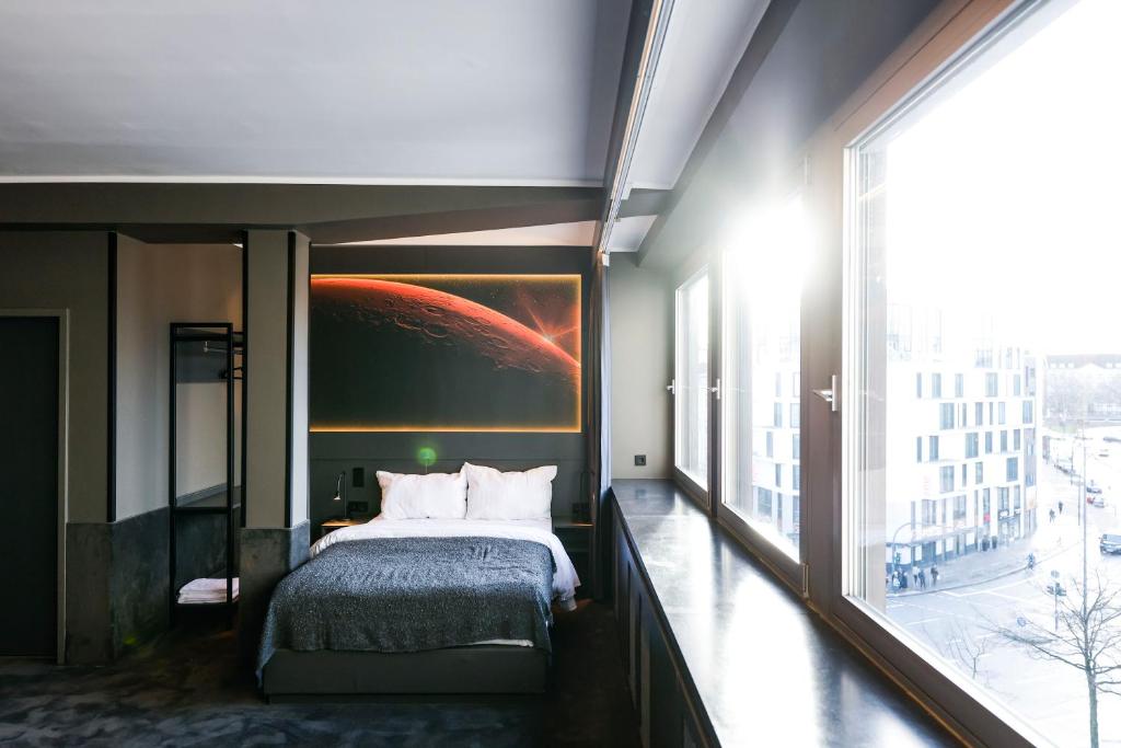 een slaapkamer met een bed en een groot raam bij Sleephotels Cosmos in Hamburg
