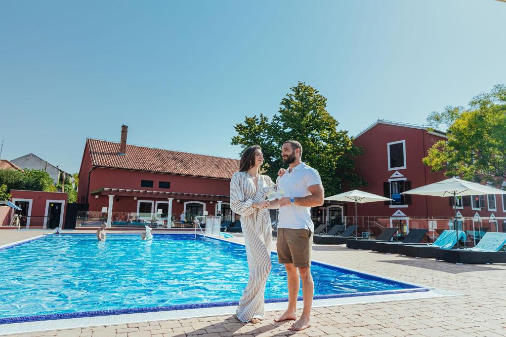 mężczyzna i kobieta stojący obok basenu w obiekcie Hotel Villa Donat w mieście Sveti Filip i Jakov
