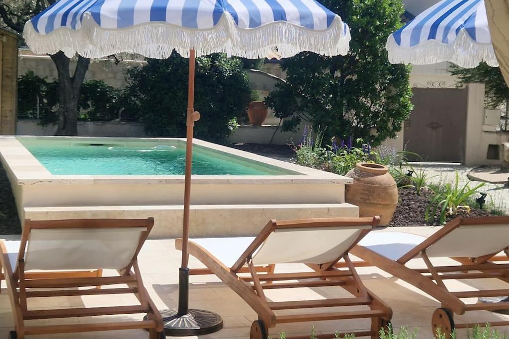 deux chaises et un parasol à côté d'une piscine dans l'établissement Magnifique maison provençale haut standing avec piscine, jardins, garages fermés, à Sablet