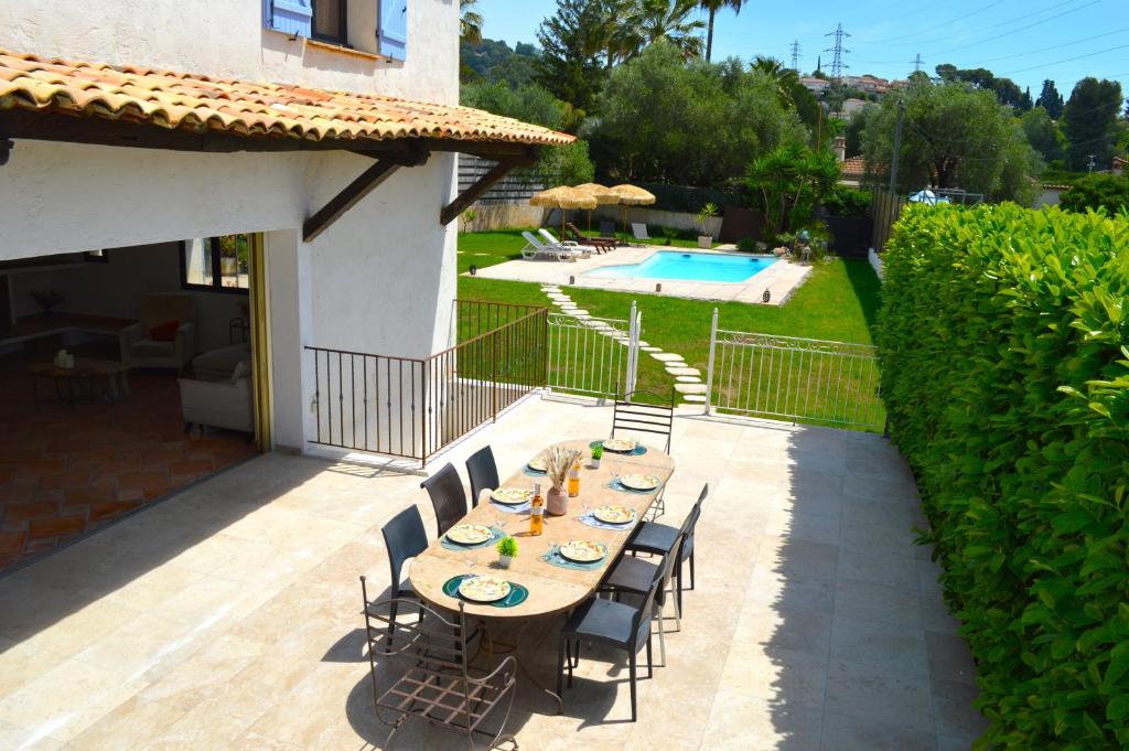 - une table et des chaises sur une terrasse à côté de la piscine dans l'établissement Villa 5 suites et piscine à Mougins, à Mougins