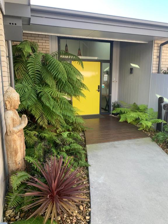 a plant in front of a building with a yellow door at Parkside Boutique Lodge in Rotorua