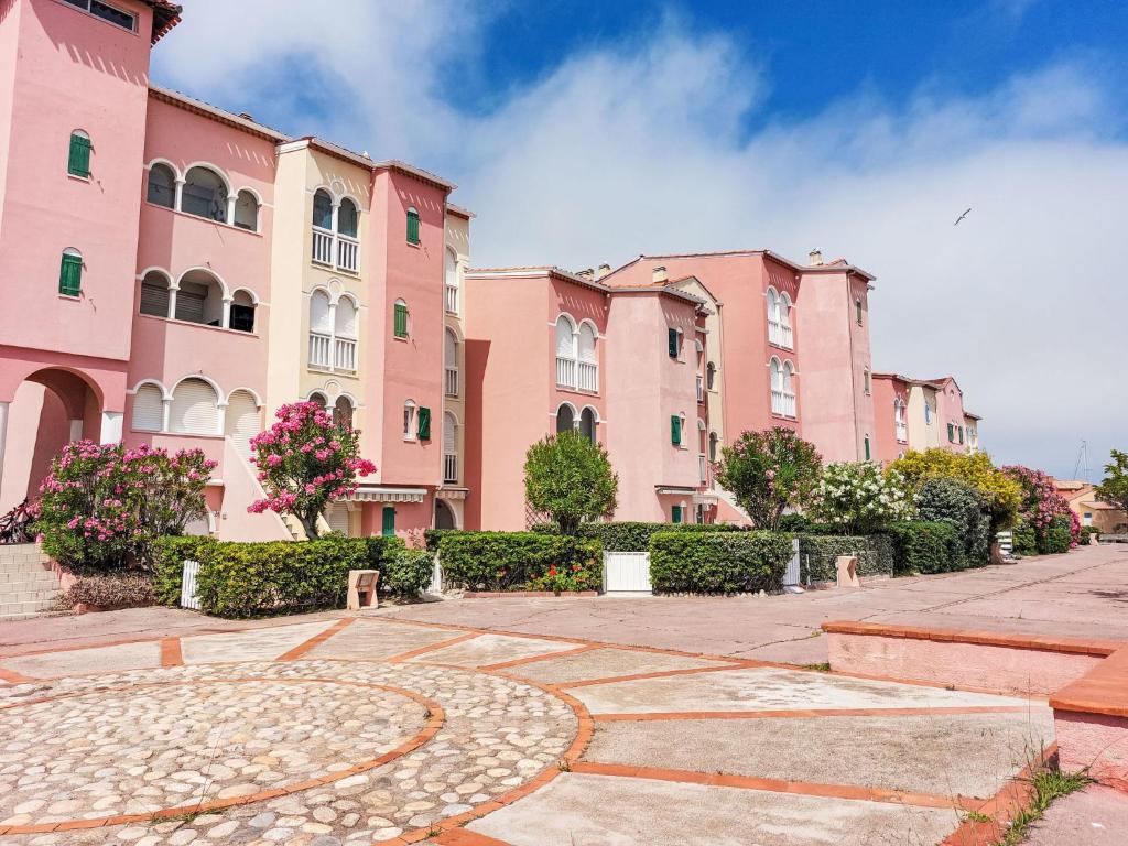 Une rangée de bâtiments roses dans une rue dans l'établissement Apartment Pointe Vermeille-1 by Interhome, au Barcarès