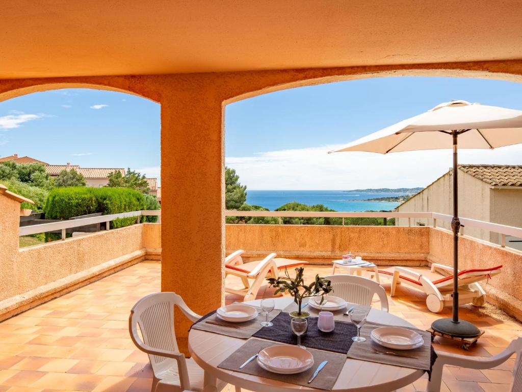 un patio avec une table, des chaises et un parasol dans l'établissement Apartment Les Coteaux de la Nartelle-13 by Interhome, à Sainte-Maxime