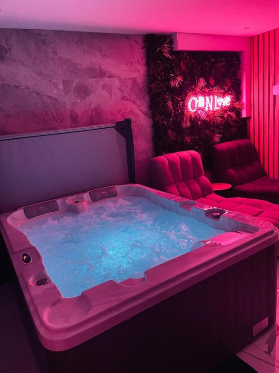 un bain à remous dans une pièce avec un canapé et une enseigne au néon dans l'établissement Chill N Love prox EuropaPark et Rulantica Strasbourg Colmar, à Rossfeld