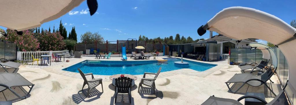 eine Terrasse mit einem Pool und Stühlen sowie ein Gebäude in der Unterkunft 2 bedrooms villa with shared pool enclosed garden and wifi at Turis in Turís