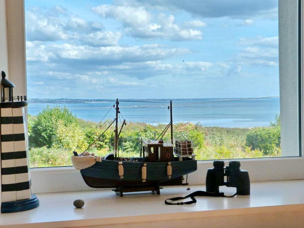 un bateau jouet assis devant une fenêtre dans l'établissement 473-Villa, 100m du GR34 Superbe vue mer, à Esquibien