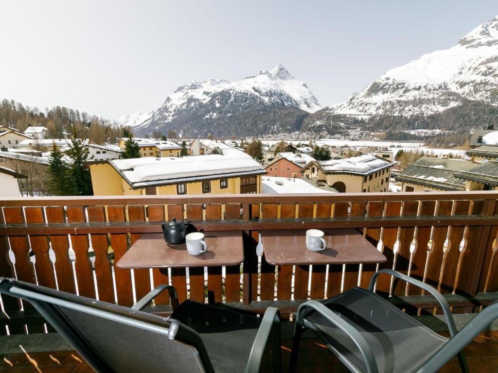 a table and chairs on a balcony with snow covered mountains at Apartment Residenza Chesa Margun 79-3 by Interhome in Surlej