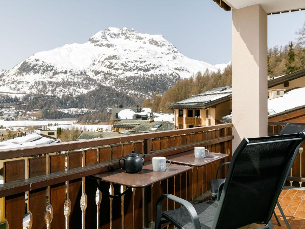 a table and chairs on a balcony with a snow covered mountain at Apartment Residenza Chesa Margun 79-3 by Interhome in Surlej