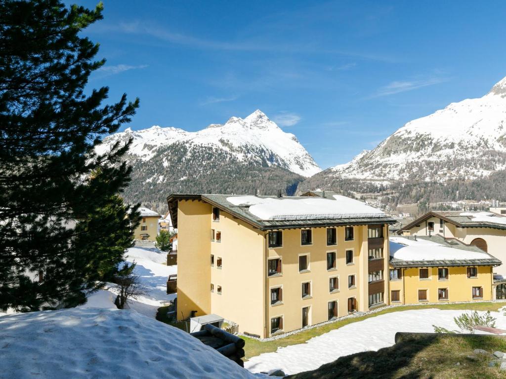 a building with snow covered mountains in the background at Apartment Residenza Chesa Margun 77-2 by Interhome in Surlej