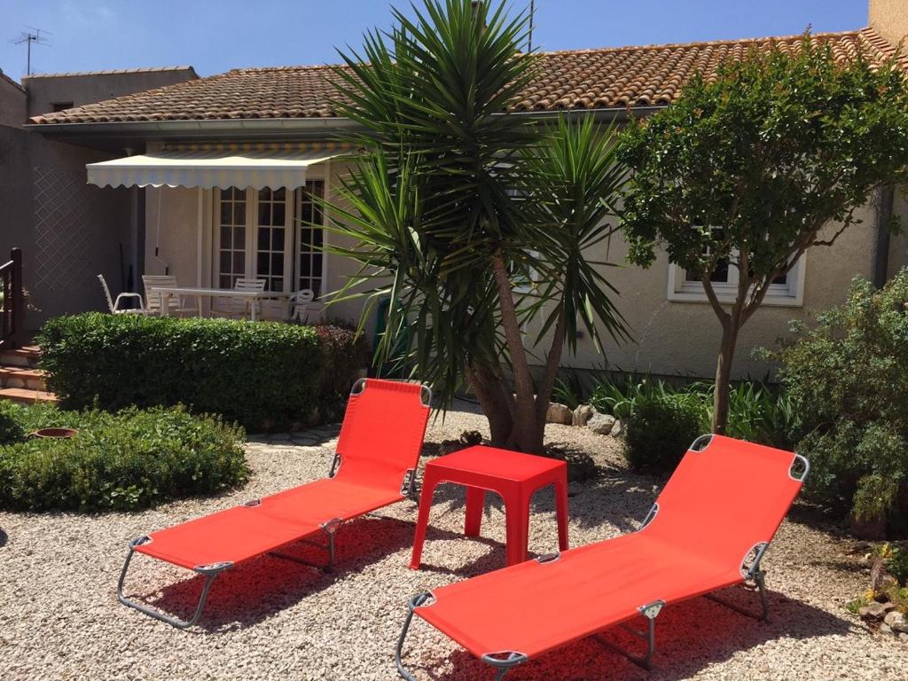 Deux chaises rouges et une table rouge devant une maison dans l'établissement Villla plain pied climatisée spacieuse 6 pers proche des plages - V0303, à Vias