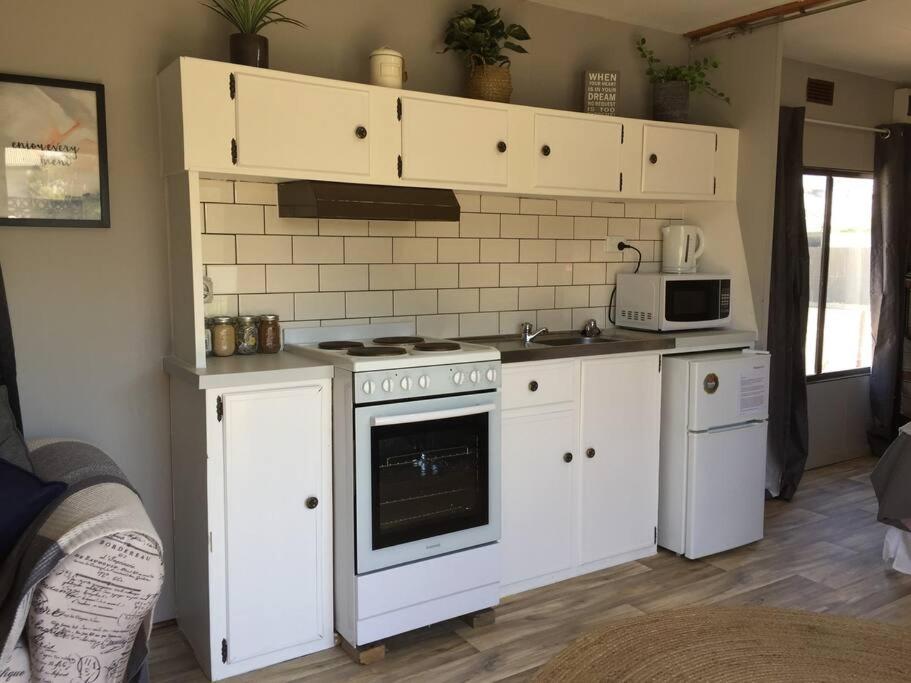 海伊Cute Private Studio Flat with AIRCON!的厨房配有白色橱柜、炉灶和微波炉。