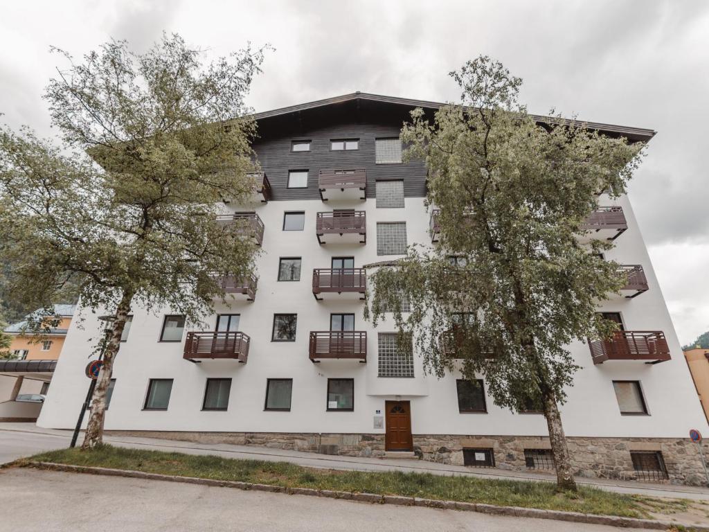 a white building with balconies and two trees at Apartment Kern by Interhome in Bad Hofgastein