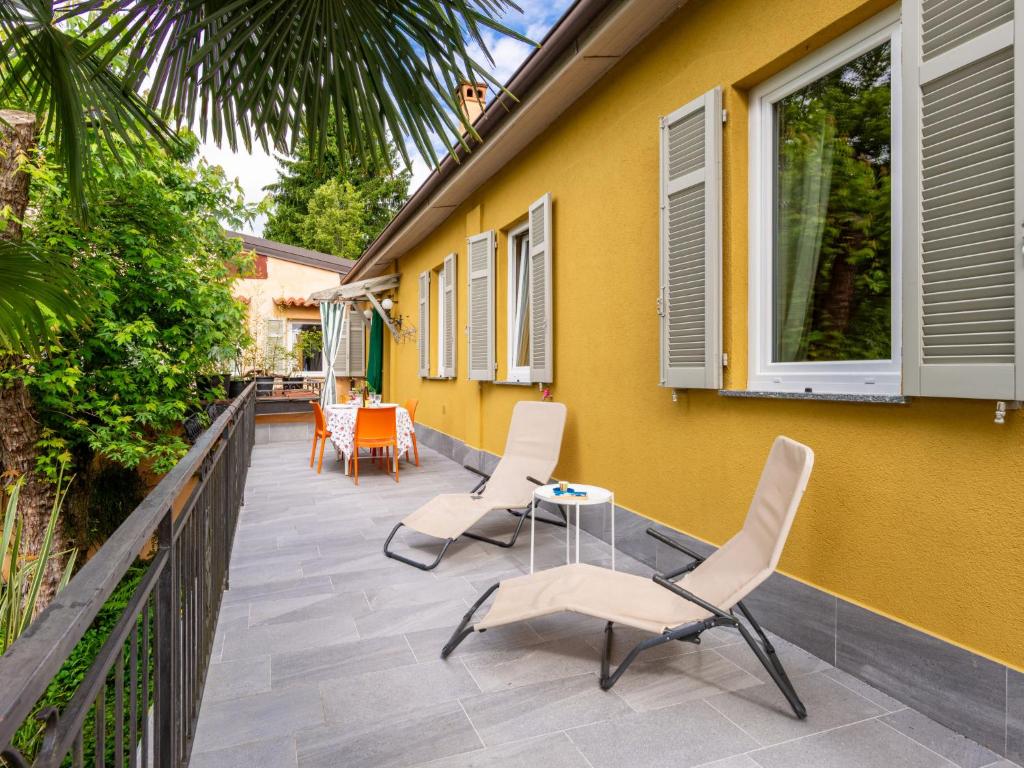 una casa amarilla con sillas y una mesa en el patio en Holiday Home Atelier-1 by Interhome, en Invorio Inferiore