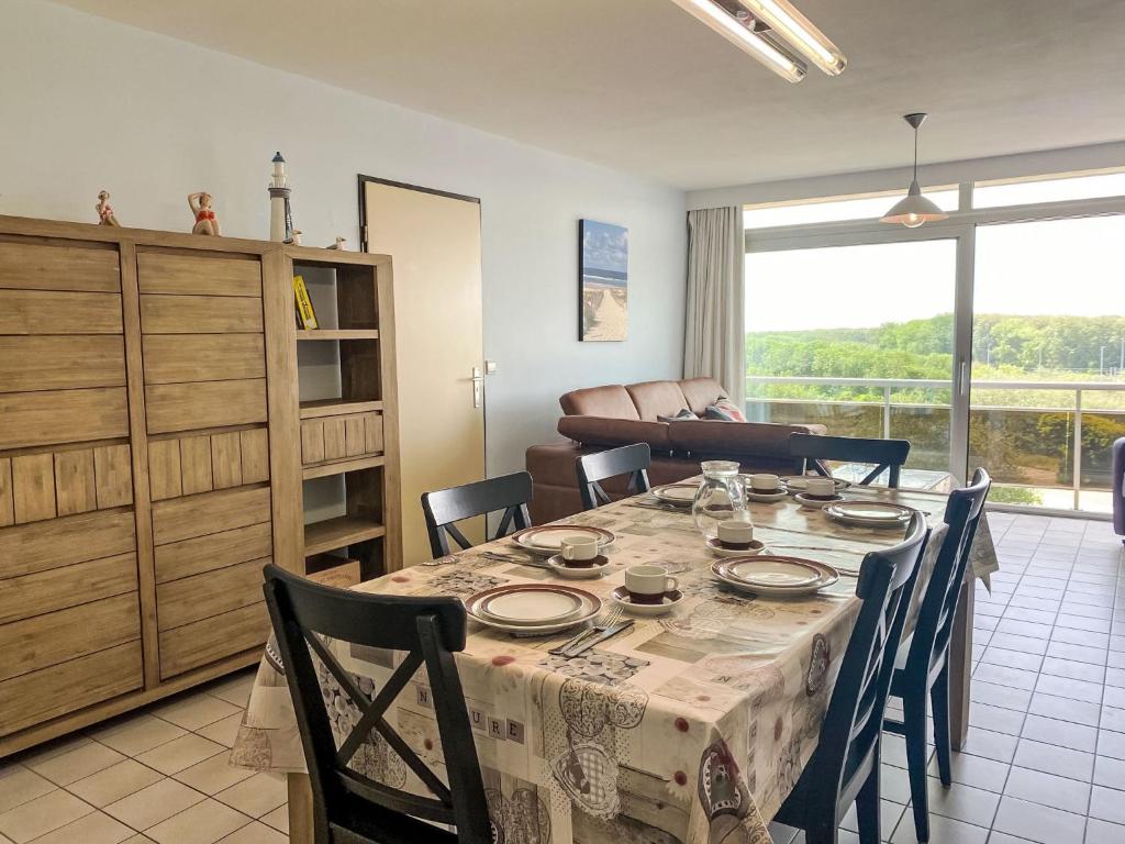 un comedor con mesa y sillas y una habitación con ventana en Apartment Ref 602 by Interhome, en Bredene