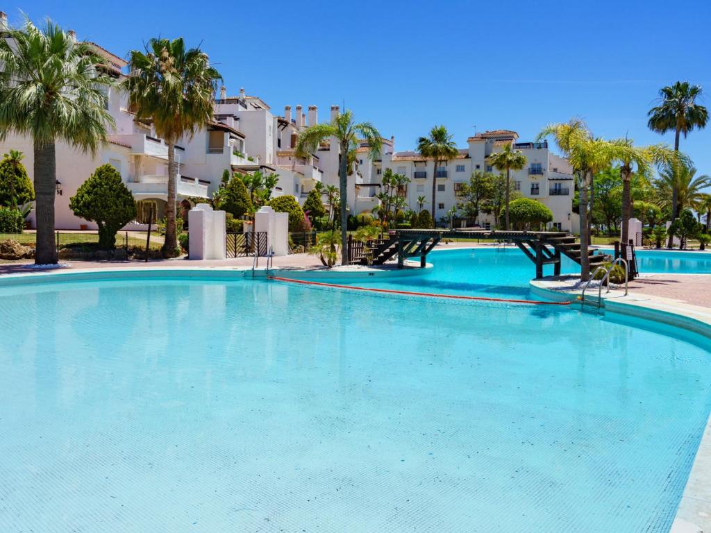 a large swimming pool with palm trees and buildings at Apartment Las Adelfas by Interhome in Marbella