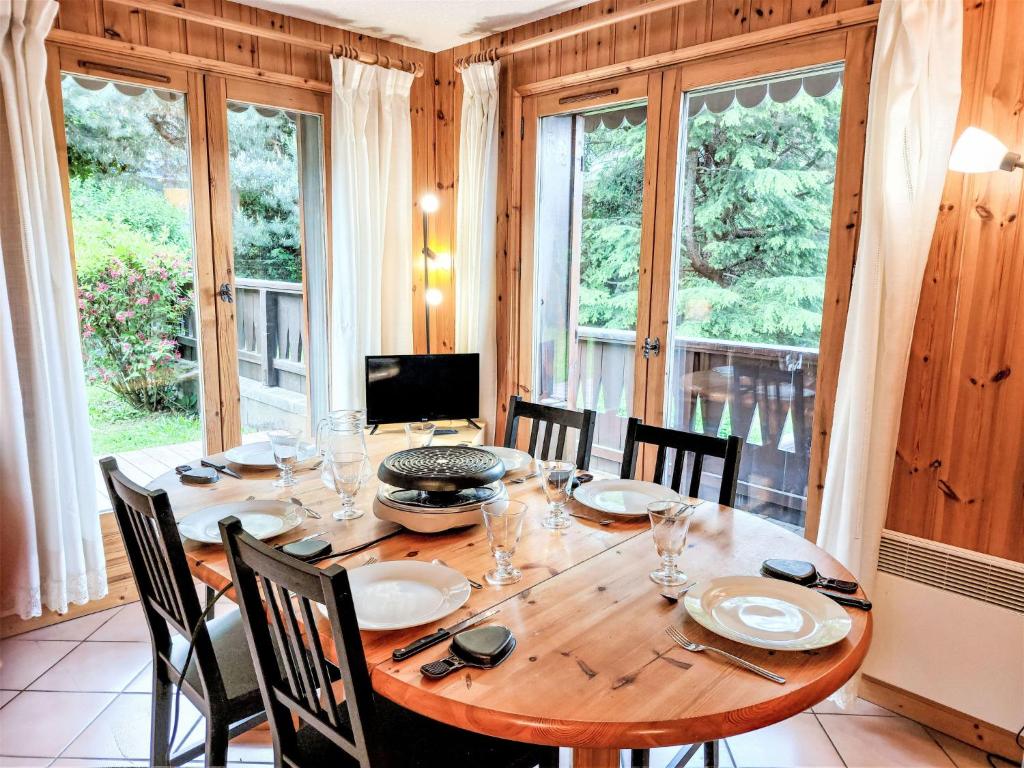 une salle à manger avec une table, des chaises et des fenêtres dans l'établissement Apartment Jardins Alpins 8 by Interhome, à Saint-Gervais-les-Bains