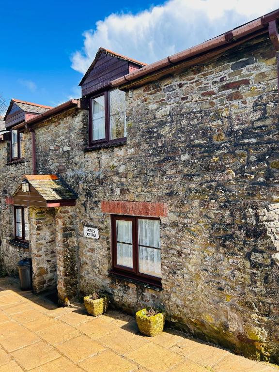 an old stone building with windows on the side of it at Rosie's cottage in Woolfardisworthy